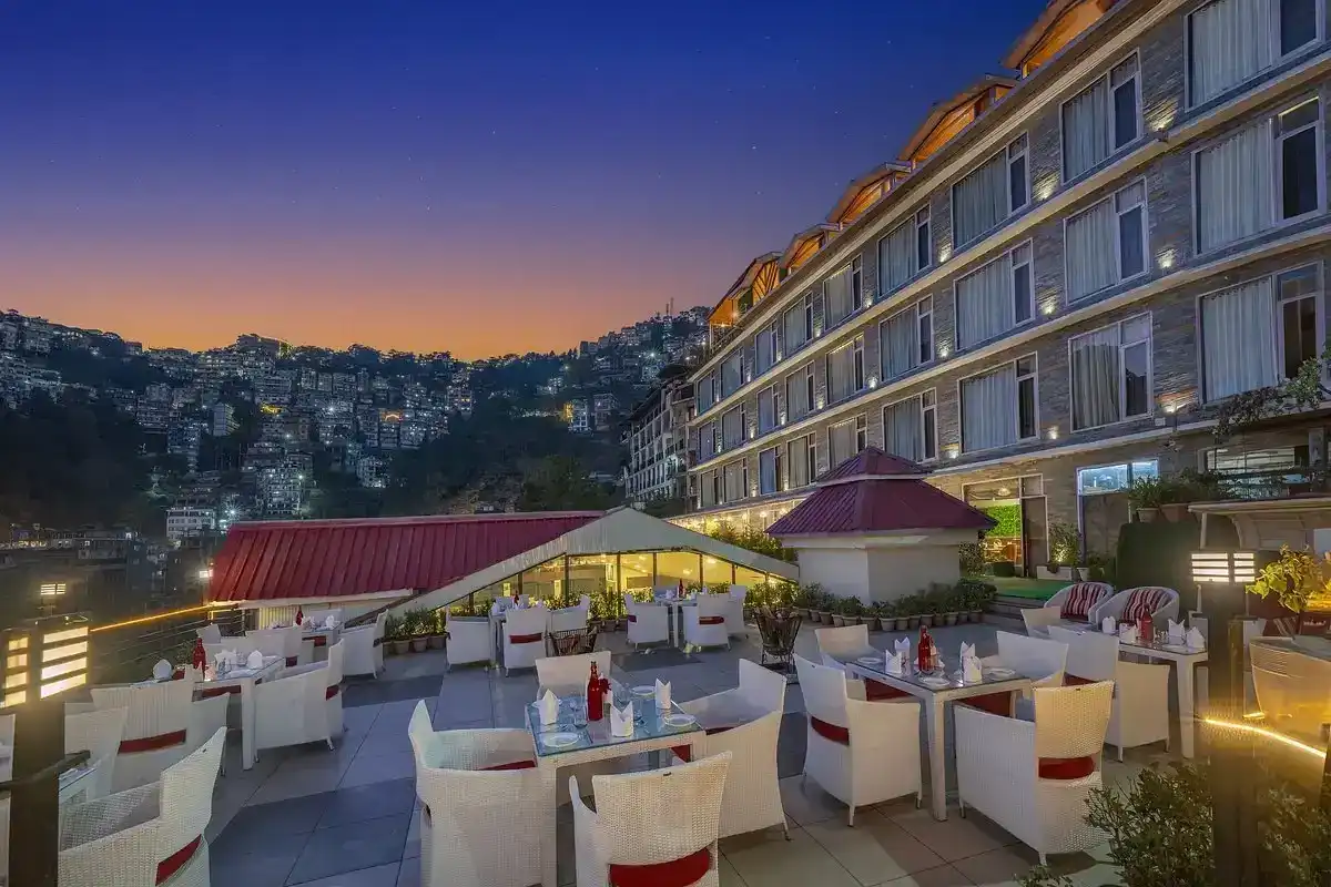 Rooftop restaurant with white seating and city lights at dusk