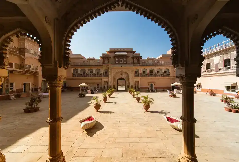Courtyard of a historic Indian palace with ornate arches and potted plants.