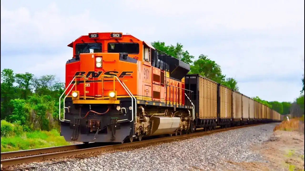 BNSF orange freight train locomotive with a long line of cargo cars on tracks